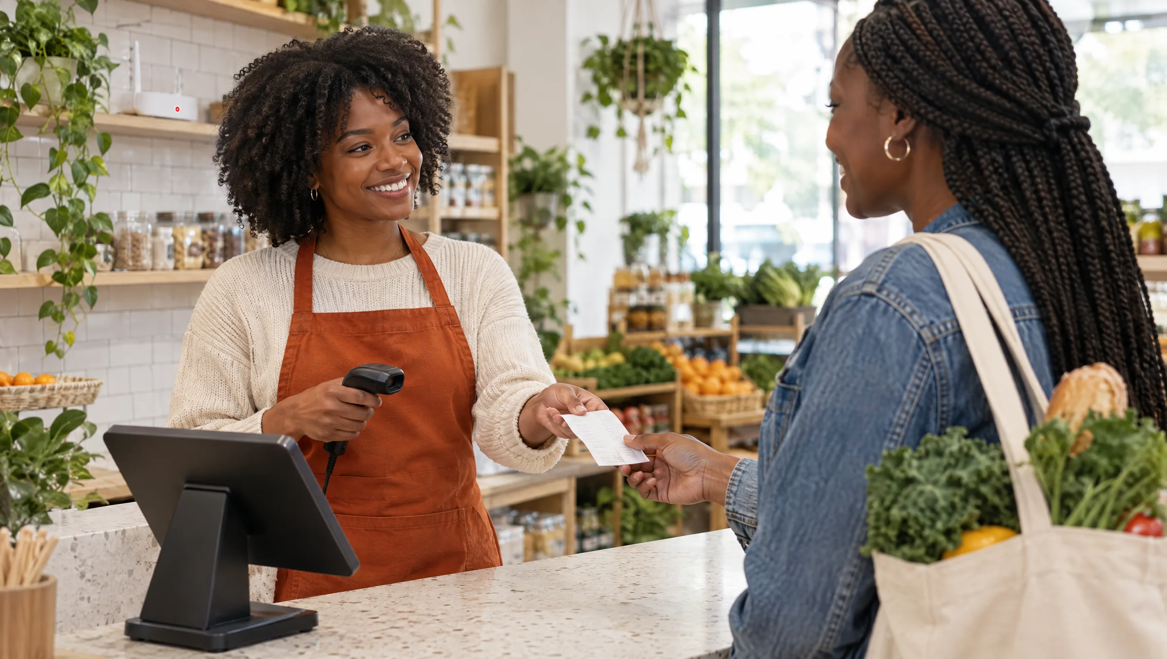 Une caissière souriante, scanner en main, remet un ticket à une cliente au comptoir d'une épicerie lumineuse